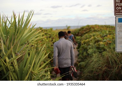 People walking down a path to the beach