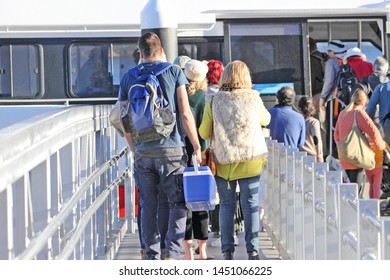 People Walking Up A Gang Plank Boarding A Ferry