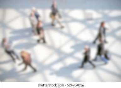 People walking, generic background with an intentional blur effect applied. Humans and location not recognizable.