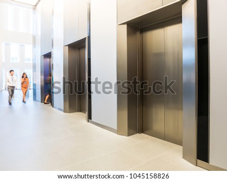 People are walking in office past elevators, Modern steel elevator cabins in a business lobby or Hotel, Store, interior, office,perspective wide angle.