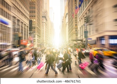 People walking on 7 th av. and West 34 th crossroad in Manhattan before sunset - Crowded streets of New York City on rush hour in urban business area - Radial blur composition with focus on background