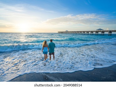 People walking on the beach. Couple holding hands  standing on the beautiful beach at sunrise. Summer beach scenery. Juno Beach, Florida, USA.