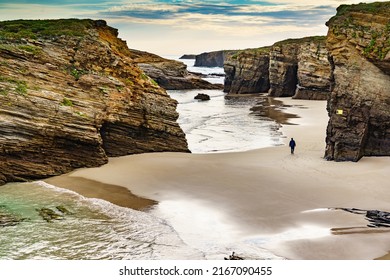 People walking on Cathedrals Beach at low tide, Playa las Catedrales in Ribadeo, province of Lugo, Galicia. Cantabric coast in northern Spain. Tourist place.