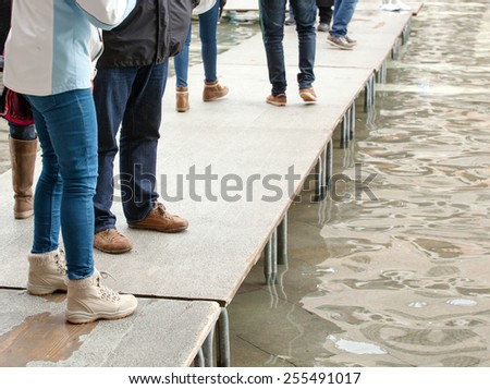People walking on catwalk in Venice during the high tide.