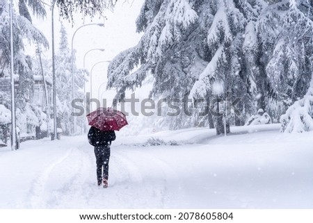 People walking on a city street during heavy snow storm. Climate change, extreme weather. Storm Filomena in Madrid. Arturo Soria area