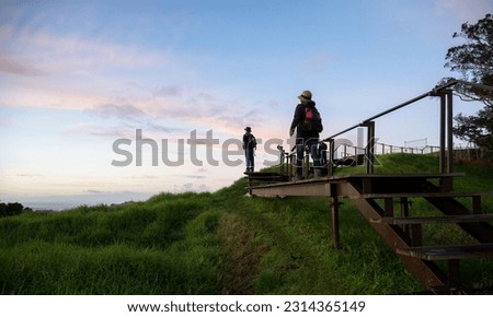 People walking on raised boardwalk around the crater at Mt Eden summit. Auckland.