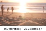 People walking on sandy Ocean Beach by pier at sunset, California coast, USA. Unrecognizable defocused family silhouettes in bright sun light, vacations on shorein sunshine. Sunlit sea water waves.