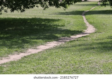 People Walking On A Trail In An Open Green Field