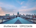 People walking over Millennium bridge at dusk. St Pauls cathedral in the background.