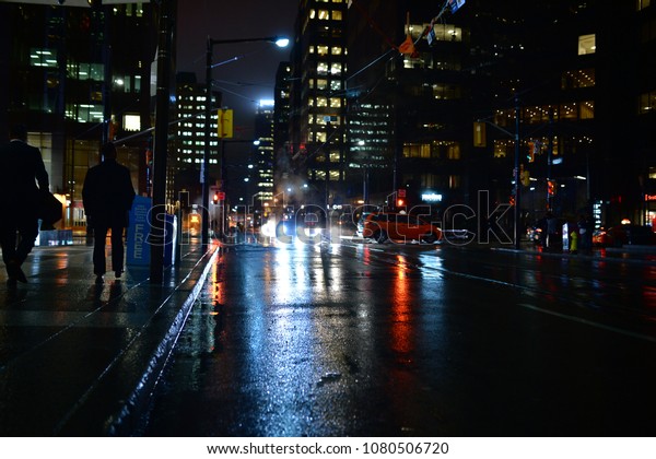 人々は雨の中 夜になると街頭を歩き 明かりが水たまり に反射している 赤い青緑と金色のディストピアのネオノワールのシーン 背景に高層ビルと グレートから煙 の写真素材 今すぐ編集