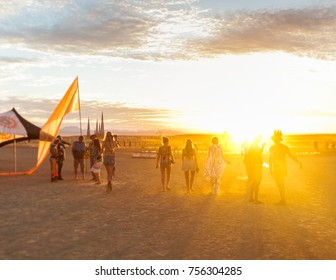 People walking towards sunset at a festival in the desert