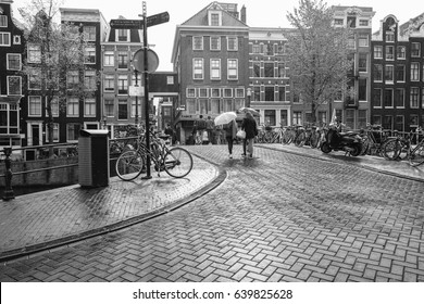 People walking under the rain on street in Amsterdam, Holland, black and white photography - Powered by Shutterstock