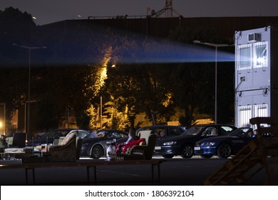 People Are Watching A Movie In A Car Cinema In The Moonlight.