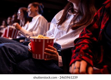 People are watching a movie in cinema. They are eating popcorn and drinking juices - Powered by Shutterstock