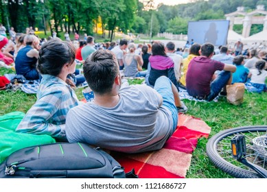 people watching movie in open air cinema in city park