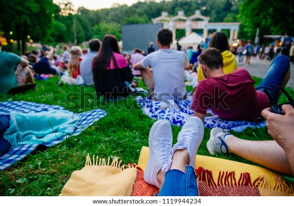 people
watching movie in open air cinema in city
park