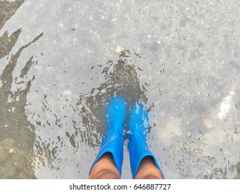 A People Wear Blue Rubber Boots Walk Trough The Flood.