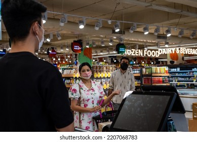 People Wearing Masks, Wait In Line At The Check Out Counter At A Supermarket.