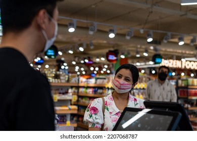 People Wearing Masks, Wait In Line At The Check Out Counter At A Supermarket.