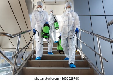 People wearing protective suits disinfecting stairs with spray chemicals to prevent the spreading of the coronavirus