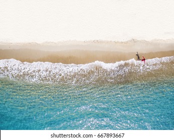 People Wearing Red Shirts Walking Footprints On The Beach White With Blue Sea Waves , Aerial View .