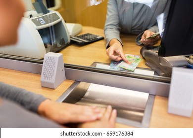 People, Withdrawal, Money, Saving And Finance Concept - Clerk Counting Swiss Francs Cash At Bank Office Or Currency Exchanger