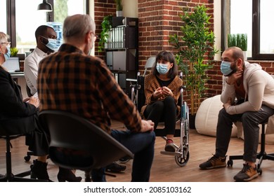 People And Woman Sitting In Wheelchair Having Discussion At Aa Meeting. Multi Ethnic Patients Attending Conversation With Psychiatrist At Support Group Therapy During Covid 19 Pandemic.