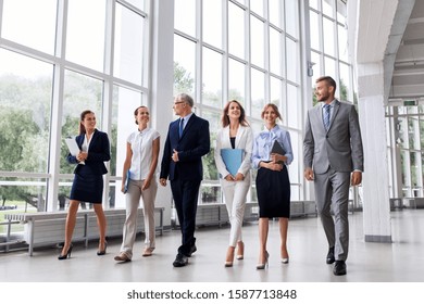 People, Work And Corporate Concept - Business Team With Folders Walking Along Office Building And Talking