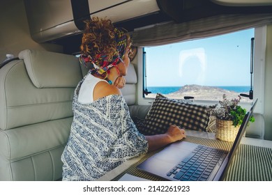 People In Work And Travel Online Modern Activity Business Lifestyle. Woman Looking Outside From Camper Van Interior Sitting At The Table With Laptop Computer. Concept Of Digital Nomad Life