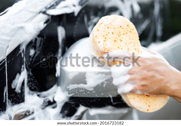 people worker man holding hand yellow\
sponge and bubble foam cleanser window for washing car. Concept car\
wash clean. Leave space for writing messages.\
