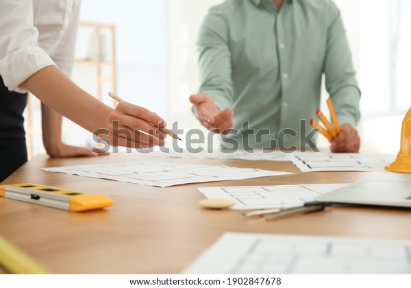 People working with construction drawings at\
table, closeup
