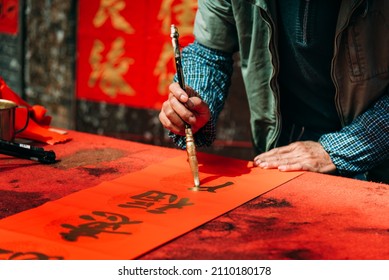 People write Spring Festival couplets with brushes with gold lacquer to celebrate Chinese New Year. Chinese characters"yi" "fu"mean good fortune. - Shutterstock ID 2110180178