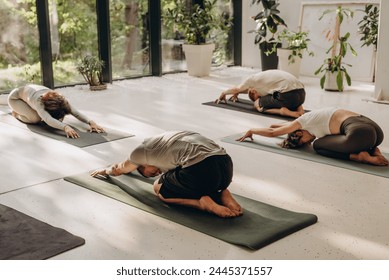 People with yoga coach stretching body during practice - Powered by Shutterstock