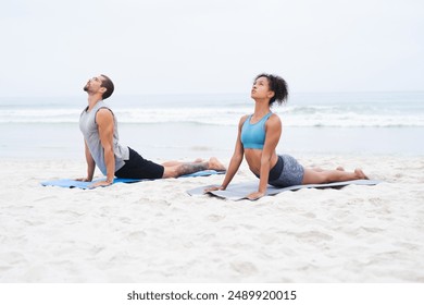 People, yoga and outdoor with practice, calm and wellness in cobra pose, wellbeing and health. Woman, man and beach in together, session and physical activity for meditate and stretch in zen or peace - Powered by Shutterstock