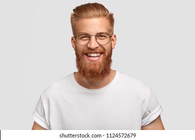 People, Youth, Positiveness Concept. Happy Male With Long Thick Ginger Beard, Has Friendly Smile, Rejoices Having Day Off For His Hobby, Expresses Happiness, Stands Alone Against White Wall.