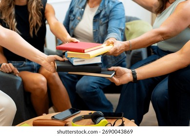 People's hands exchanging stack of books at a book club gathering, symbolizing sharing, learning, and community