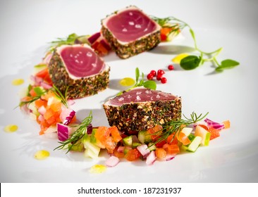 Pepper coated and lightly seared raw tuna chunks served with finely chopped vegetable salad and sprinkled with sea salt