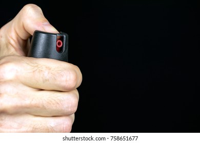 pepper gas in the hand of a young man in a black jacket CS spray self-defense Tear gas concept, copy space, close up, selective focus , blurred dark background