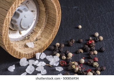 Pepper Mill, Sea Salt And Pepper Grains On Dark Stone Surface Close Up