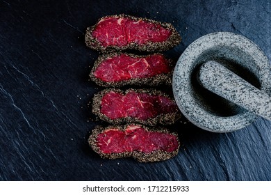 Pepper Steaks On Stone With Mortar Bowl And Pestle Above