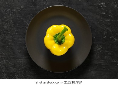 Pepper sweet yellow Bulgarian whole on gray plate, top view dark background, with space to copy text.