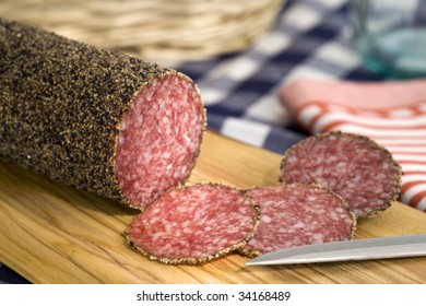 Peppered Salami And Slices On Cutting Board With Knife