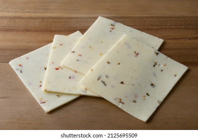Pepperjack Cheese Slices On A Cutting Board