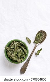 Peppermint dried leaves tea viewed from above. Spoon and bowl with herbal mint tea ingredients. Top view