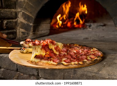 Pepperoni Pizza Cheese Pull In Front Of Wood Oven With Fire In Background