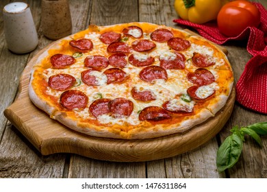 Pepperoni pizza on board on old wooden table - Powered by Shutterstock