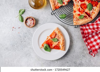 Pepperoni pizza slice on plate on light gray background. Traditional Italian fastfood. With red white checkered towel. Top view. - Powered by Shutterstock