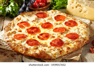 Pepperoni oder Salami Pizza - hausgemachter Pizzateig mit Salami Wurstscheibe und Käse. Italienische Pizza auf Backpapier mit Tomate und Käse auf Holztisch. Fast-Food-Dinner im rustikalen Stil