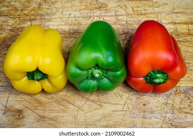 Peppers in three colours on a kitchen breadboard. Preparing vegetables for a healthy salad.