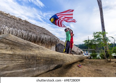 Perak , Malaysia - 18 August 2017 - Aboriginal Kids Show A Spirit Of Independence Of Malaysia By Flying Their National Flag In Rural Area In Deep Rain Forest Royal Belum Malaysia. 